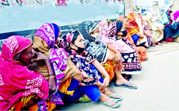 Needy women wait for food aid sitting beside a footpath at the city's Gopibagh area in Dhaka during a government-imposed nationwide shutdown on Friday. Poor people hit hardest by the government's sweeping measures to contain the Covid-19 outbreak in the