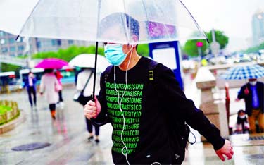 People wearing face masks exit a subway station during a rainy day, following an outbreak of the coronavirus disease in Beijing on Saturday.