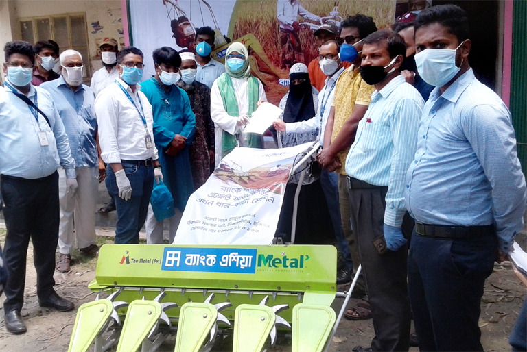 Musammat Rahima Akhter, Upazila Nirhabi Officer of Sreenagar, on behalf of Bank Asia handing over harvester machine to Nazma Begum, a female farmer of Kamargaon village at the Upazila Muktijoddha Chattor recently. Bipul Sarker, Head of Sirajdikhan Branch,