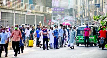 Employees of shopping malls and markets opened in limited scale are seen waiting for transports to return to their respective destinations defying social distancing after closing their workplace. This picture was taken from city's Gulistan area on Monday
