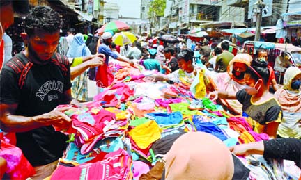 Shoppers throng to a footpath shop at Lalbagh in the capital on Monday without maintaining the physical distance to protect.