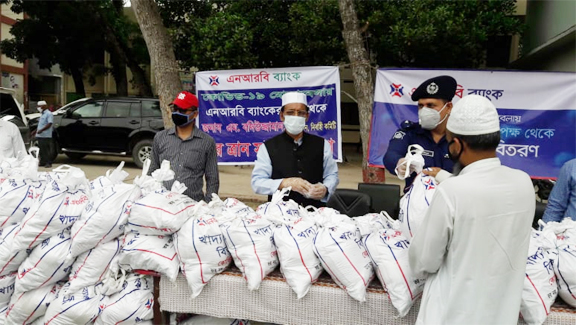 Saidur Rahman, Superintendent of Police of Gopalgonj District on behalf of NRB Bank Ltd, distributing essential foods among under privileged and ultra-poor people at the bank's Gonapara Branch premises on Tuesday. Gopalgonj Sador Upazila Mayor Kazi Liako