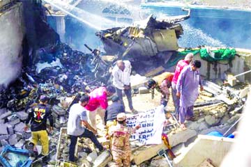 Rescue workers cover the body of a victim they recovered from the rubbles after a Pakistan International Airlines flight crashed in a residential neighbourhood in Karachi on Friday. Internet photo