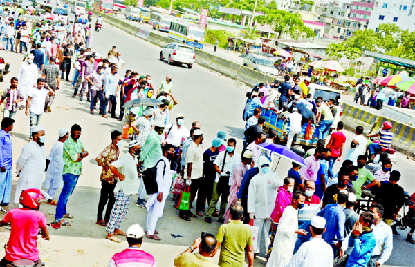 Commuters wait for public bus at the capital's Rayer Bazar on Monday, a day after the authorities reopened offices and transport services in a restricted manner.