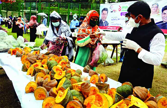 Councilor of 26 No Ward of DSCC Hashibur Rahman Manik handing over vegetables among the low-income people free of cost after inaugurating a 'market for one minute'at Abdul Alim Playground in the city on Wednesday.