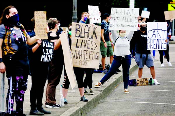 Demonstrators holding signs towards passing cars during a protest of the death of George Floyd in front of the Oregon State Capitol Building on Friday.