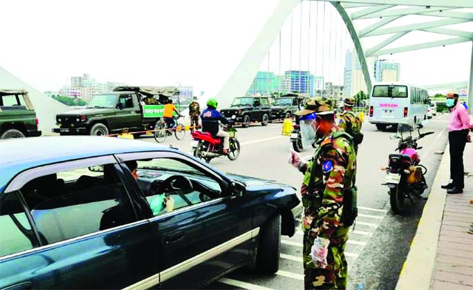 Army personnel intercept a car at Hatirjheel are in Dhaka on Saturday to aware motorists about the health guidelines issued by the government in response to the outbreak of the coronavirus pandemic in the city.