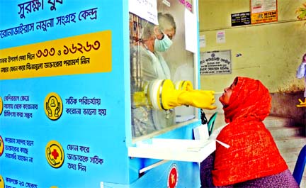 A health worker in a protective suit collects swab from a woman to get tested coronavirus. This photo was taken from a booth set up at the Paltan Community Center in Dhaka on Sunday.