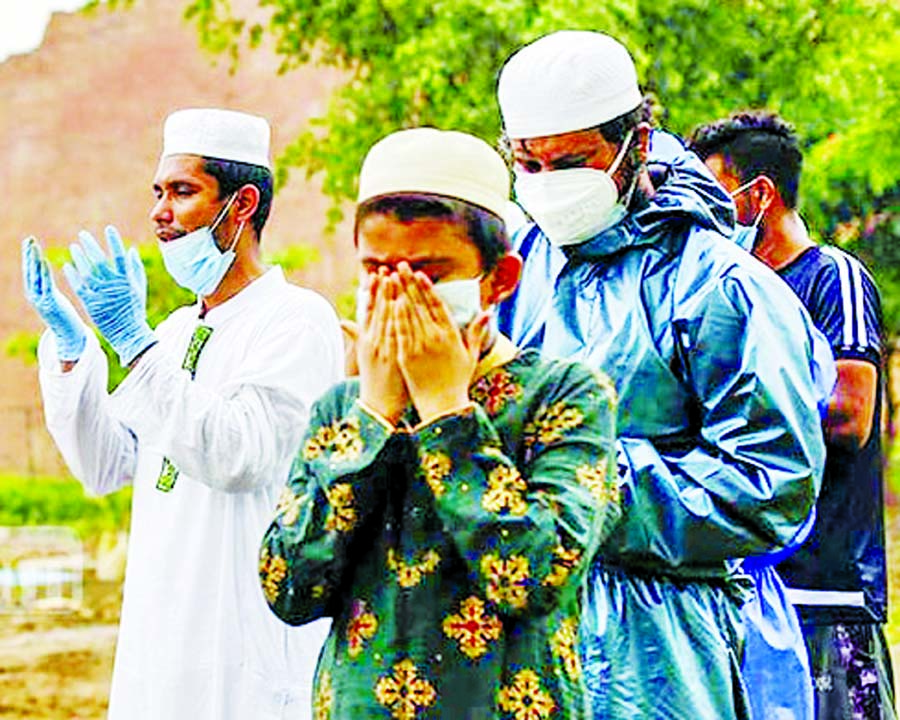 Relatives offer prayers after the burial of a patient who died from Covid-19 at Rayer Bazar Graveyard in Dhaka on Tuesday.