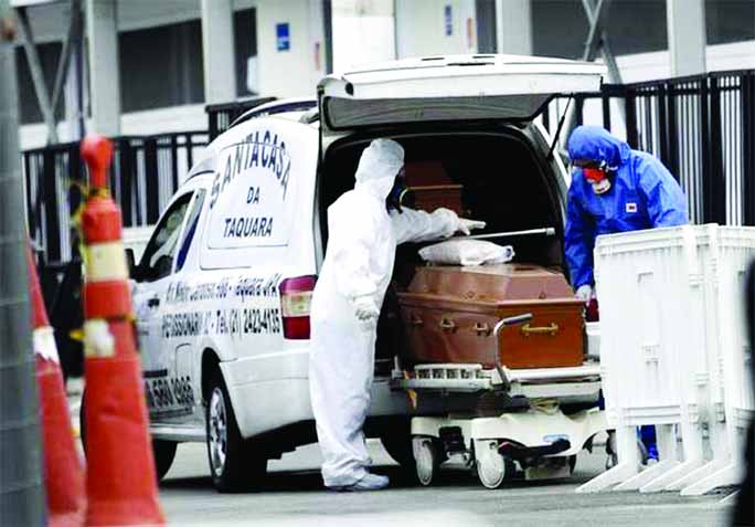 Funeral workers wearing protective gear placing the remains of a Covid-19 victim into a funeral car at a field hospital in Leblon, Rio de Janeiro.