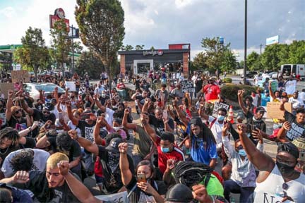 Demonstrators stop for a moment of silence on Monday outside the Wendy's in Atlanta where Rayshard Brooks was fatally shot by a police officer. Agency photo