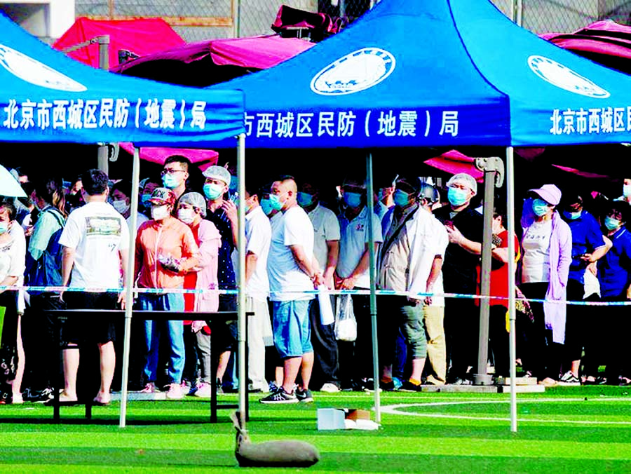 People who live near or have visited the Xinfadi Market, a wholesale food market where a new coronavirus cluster has emerged, wear facemasks while queueing for testing at the Guang'an sports centre in Beijing on Tuesday.