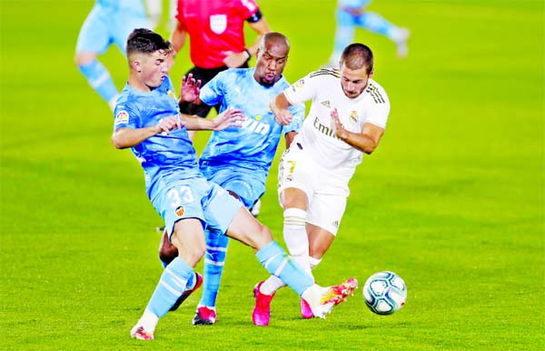 Real Madrid's Eden Hazard (right) challenges for the ball with Valencia's Hugo Guillamon (left) and Valencia's Geoffrey Kondogbia during the Spanish La Liga soccer match between Real Madrid and Valencia at Alfredo di Stefano stadium in Madrid, Spain on