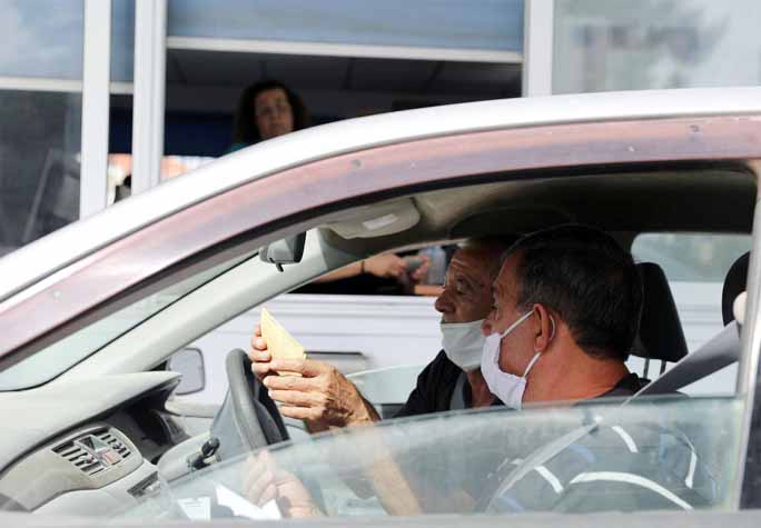 Turkish Cypriots wearing face masks look for their documents as they cross Ayios Dhometios checkpoint, as the spread of the coronavirus continues, in Nicosia on Sunday.