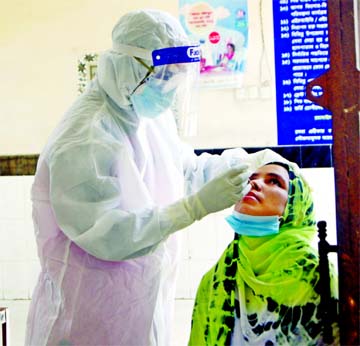 A health worker in a protective suit collects swab from a woman to get tested coronavirus in Dhaka.