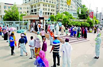 People wearing protective masks stand in a queue outside the Coronavirus testing facilitation centre of Mugda General Hospital in Dhaka on Monday.