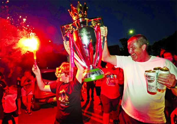 Liverpool supporters hold a replica Premier League trophy as they celebrate outside of Anfield Stadium in Liverpool, England on Thursday after Liverpool clinched the English Premier League title.