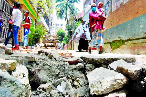 The Dhaka South City Corporation is yet to complete the development work of Singapore Road in the capital's North Mathertek area even after the work began seven months ago. This photo was taken on Friday shows that pedestrians pass through the broken roa
