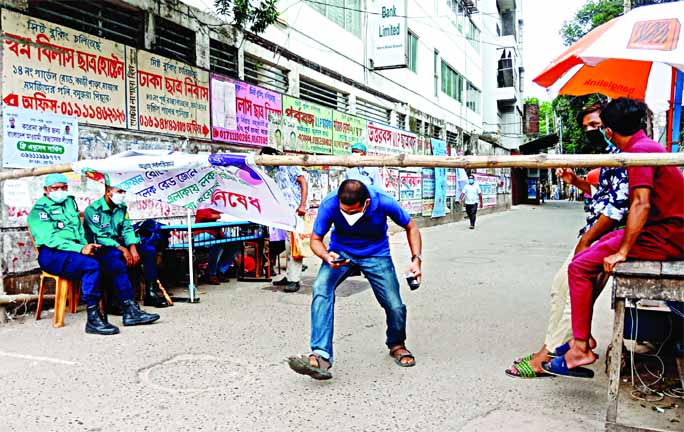 A man seen to cross lockdown area despite law-enforcers were deployed near the bamboo barricade. The snap was taken from the city's East Rajabazar on Saturday.