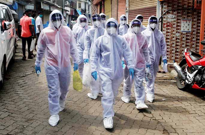 Healthcare workers wearing personal protective equipment (PPE) walk towards different localities before the start of a check-up camp for the coronavirus in Mumbai on Saturday.
