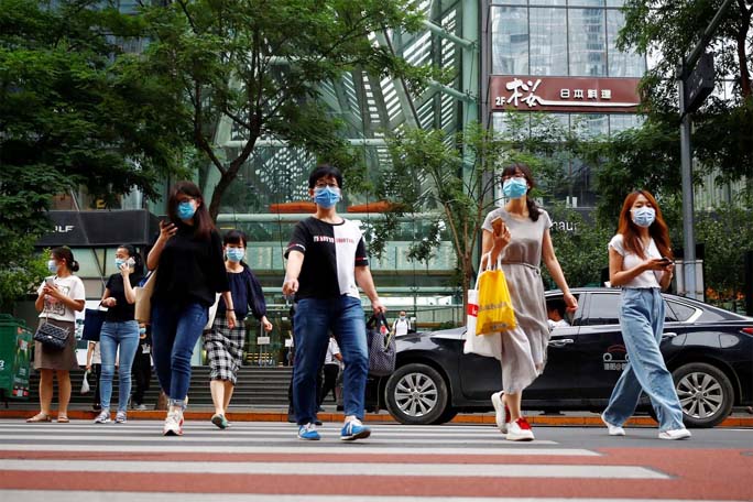 People wearing face masks leave an office building after work following a new outbreak of the coronavirus in Beijing on Monday.