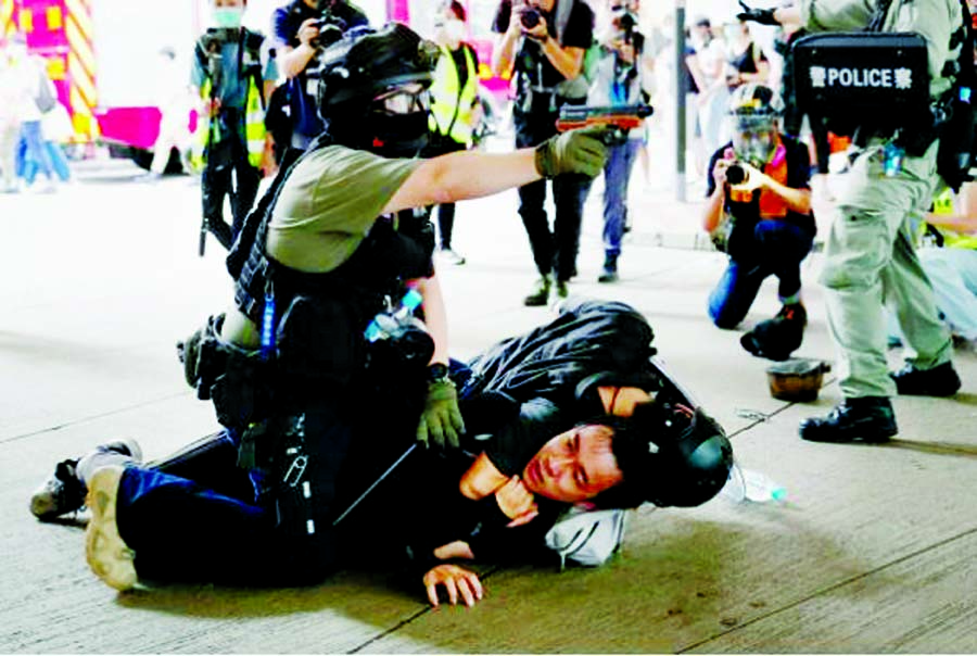 A police officer raises his pepper spray handgun as he detains a man during a march against the national security law at the anniversary of Hong Kong's handover to China from Britain in Hong Kong on Wednesday.
