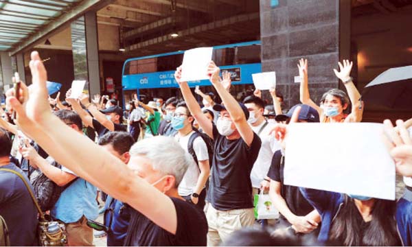 Supporters raise white paper to avoid slogans banned under China's security law as they voice support for an arrested anti-law protester outside a court on Friday. Internet