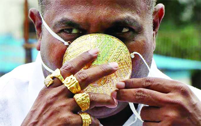 Shankar Kurhade wears his face mask made out of gold as he poses for a photograph amidst the spread of coronavirus in Pune on Saturday.