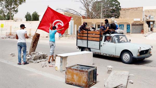 Protesters, who are demanding jobs and a share in revenue from the area's natural resources, react as they block the road which is usually used by foreign oil companies to go to the oilfield in Tataouin.