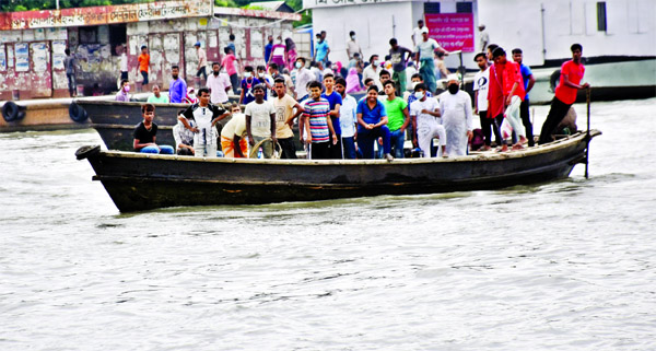 People gather on a boat defying all social distancing norms and without wearing any masks to cross the River Sitalakhya. This photo was taken from Narayanganj ferry ghat on Friday.