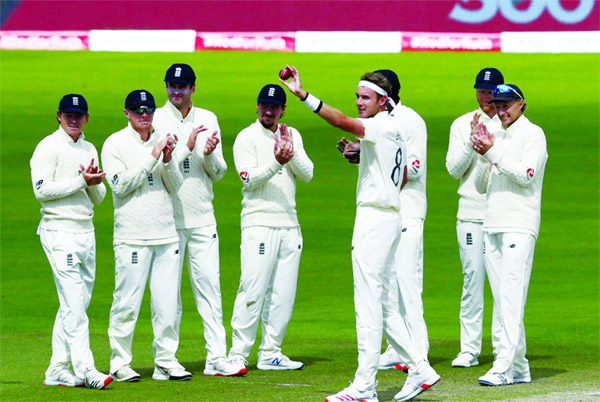 England's Stuart Broad (fourth right without cap) holds the ball to celebrate taking 500 wickets during the fifth day of the third cricket Test match between England and West Indies at Old Trafford in Manchester on Tuesday.