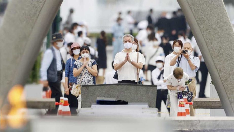 People wearing protective face masks pray for atomic bomb victims in front of the cenotaph for the victims of the U.S. 1945 atomic bombing, at Peace Memorial Park in Hiroshima, western Japan on Thursday.