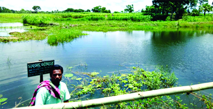 A farmer with gloomy face is seen beside his pond that washed away by rainwater which cost him Tk4 lakh loss of fish business. This photo was taken from Char Laxmipur village at Modhukhali upazila of Faridpur.