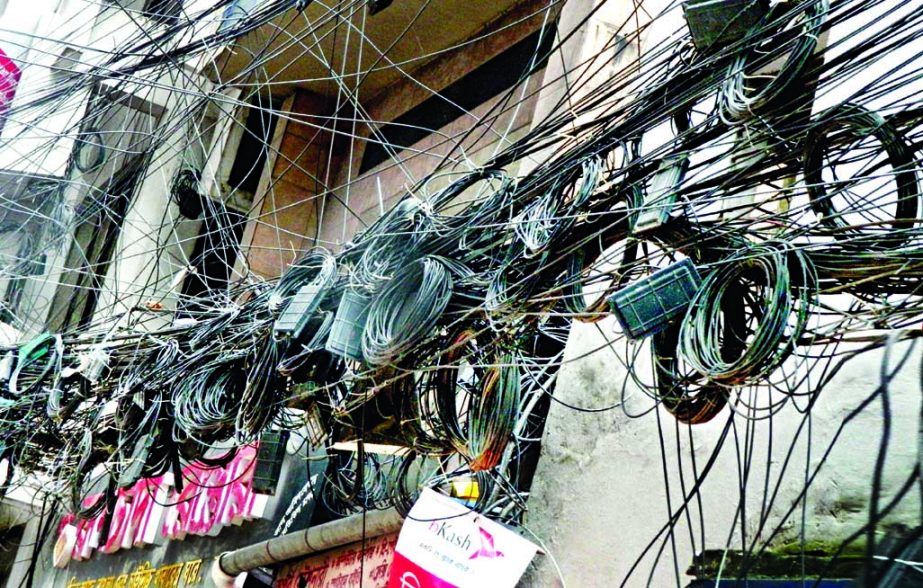 Overhead cables dangle with electric poles not only destroying the scenic beauty of the capital, but also poses high risk of fatal accident at any time. The photo was taken from Motijheel area on Tuesday.