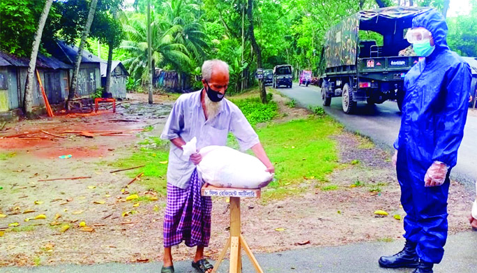 An Army personnel hands over relief to an elderly man in Jashore Area on Wednesday.