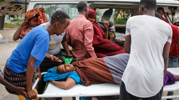 Medical workers and other Somalis help a civilian woman, who was wounded when a powerful car bomb blew off the security gates to the Elite Hotel, as she arrives at a hospital in Mogadishu, Somalia on Sunday.
