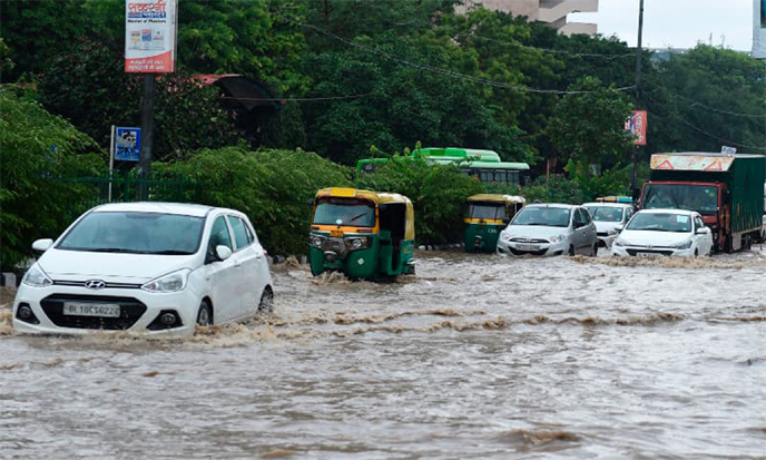 Commuters make their way along a waterlogged road following monsoon rainfalls in New Delhi on Wednesday.