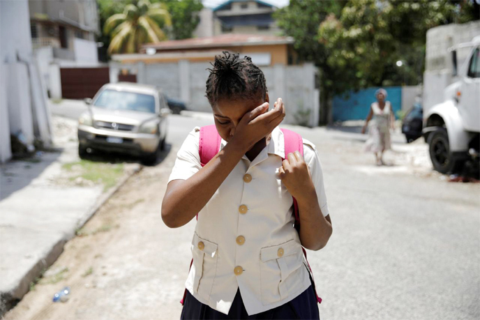 Nickerla Ambroise Etienne dries her tears, after being informed that she cannot attend school yet, as she walks along a street in Port-au-Prince, Haiti.