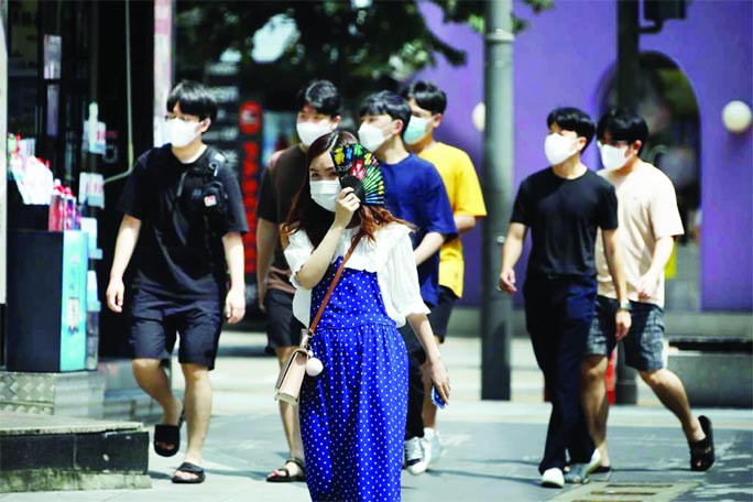 Pedestrians wearing masks to prevent the spread of the Covid-19 walk in a shopping district, in Seoul on Friday.