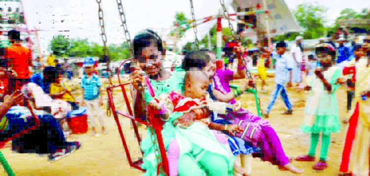 In this file photo, Rohingya refugee children board on a swing ride in the Kutupalong Refugee Camp in Cox's Bazar, Bangladesh.