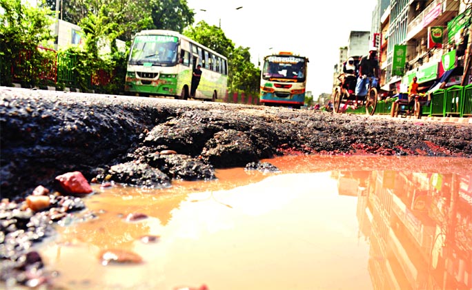 PATHETIC STATE OF ROADS IN CITY: Vehicles have to negotiate with a large pothole hidden under stagnant water on the Purana Paltan to Dainik Bangla Road in the capital. Many of the vehicles break down on their way there because of appalling state of the r