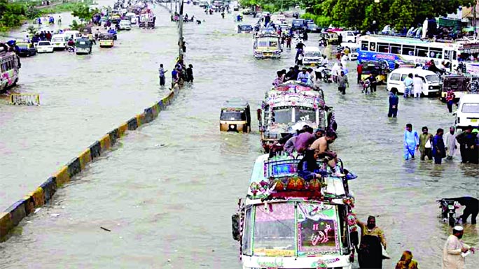 Vehicles drive through a flooded road after heavy monsoon rains in Karachi on Friday.