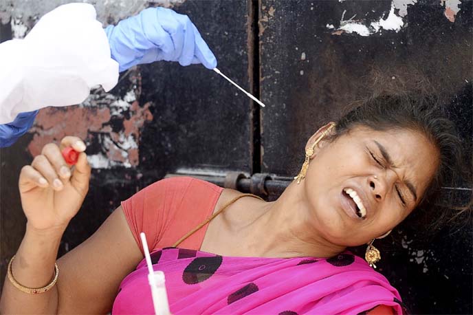 A health worker takes a swab sample from a woman to test for the coronavirus at a testing camp in a residential area, in Chennai on Sunday.