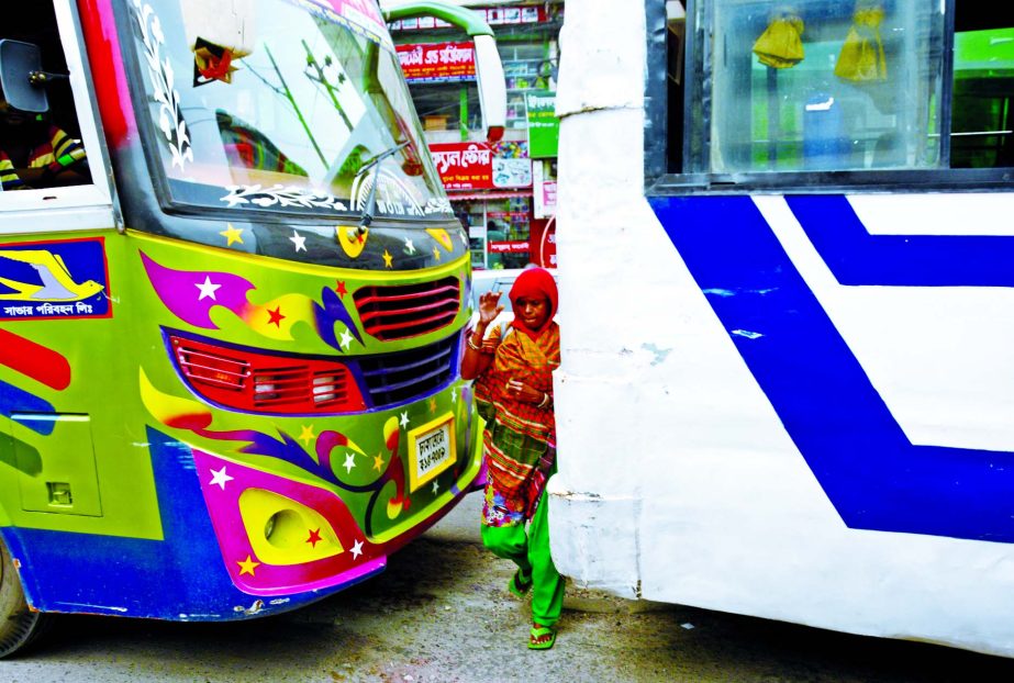 A woman walks across the city road at Purana Paltan between two buses risking terrible accident on Tuesday.