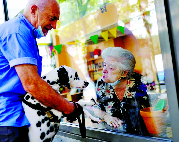 Maria de Concepcion Illa, 89, who lives in a care home, blows a kiss to Menta, the dog of her neighbour Antoni (L), 70, as they talk through a glass front at the Centre Parc nursing home after Catalonia's regional authorities announced restrictions to co