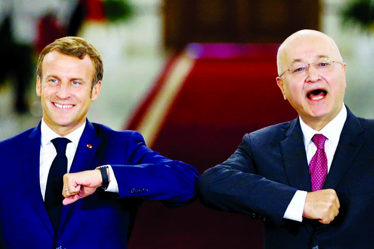 French President Emmanuel Macron and Iraq's President Barham Salihat greet each other with an elbow bump as they attend a news conference in Baghdad on Wednesday.