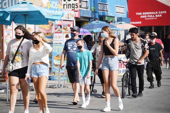 People walk on the boardwalk as many come to the beach to escape the heat wave, in Venice Beach, California on Friday.