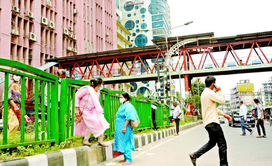Pedestrians are seen to cross the city road risking their lives although there is a foot over bridge. The photo was taken on Tuesday from near the city's Shapla Chattar in Motijheel area.
