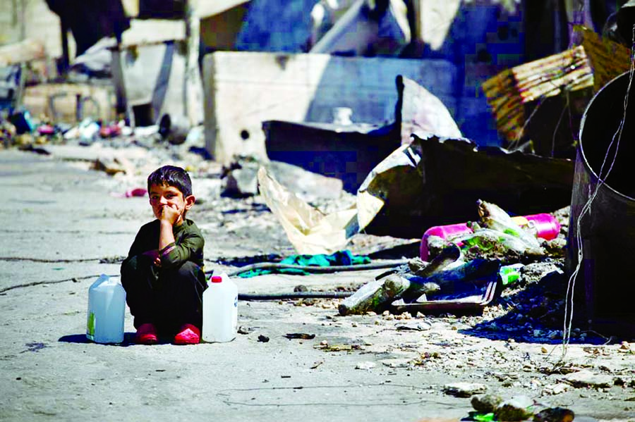 A boy with two water cans sits next to destroyed shelters following a fire at the Moria camp for refugees and migrants on the island of Lesbos, Greece on Wednesday.