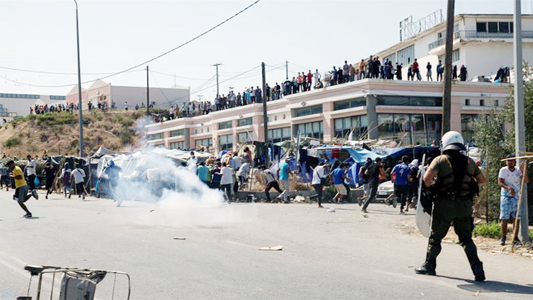 Refugees and migrants from the destroyed camp of Moria flee tear gas fired by riot police during clashes on the island of Lesbos on Friday.